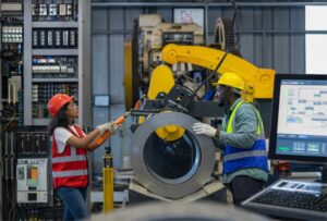 Técnicos en seguridad industrial trabajando en maquinaria automatizada en planta de fabricación con equipos de control y monitoreo