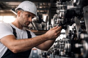 Técnico industrial con casco revisando maquinaria automatizada en planta de producción