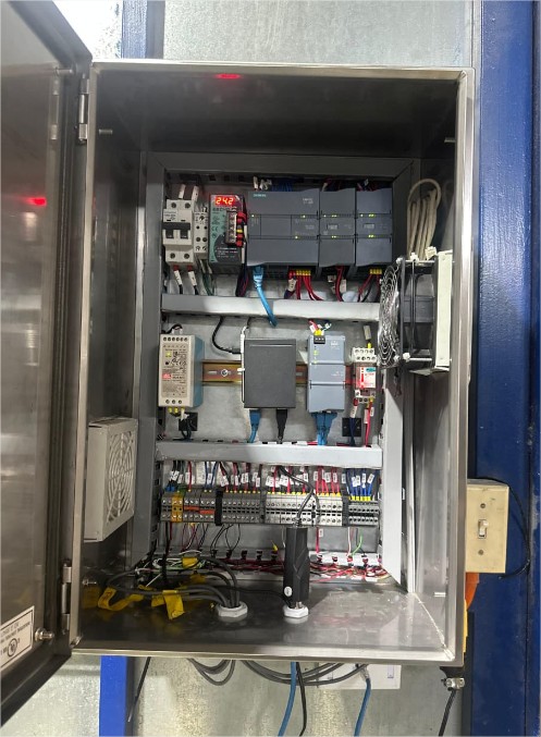 Panel eléctrico abierto mostrando componentes de automatización industrial con cables y módulos de control.