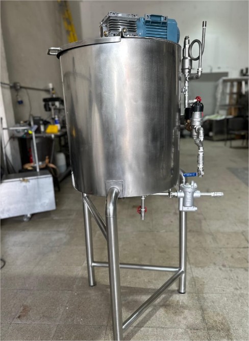 Tanque industrial de acero inoxidable con motor y tuberías para automatización industrial en planta de procesos